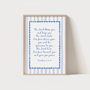 May include: A framed print with a light wood frame, featuring a blue and white striped border. The print displays a quote from Numbers 6:24-26 in blue script. The design has a soft, calming aesthetic.