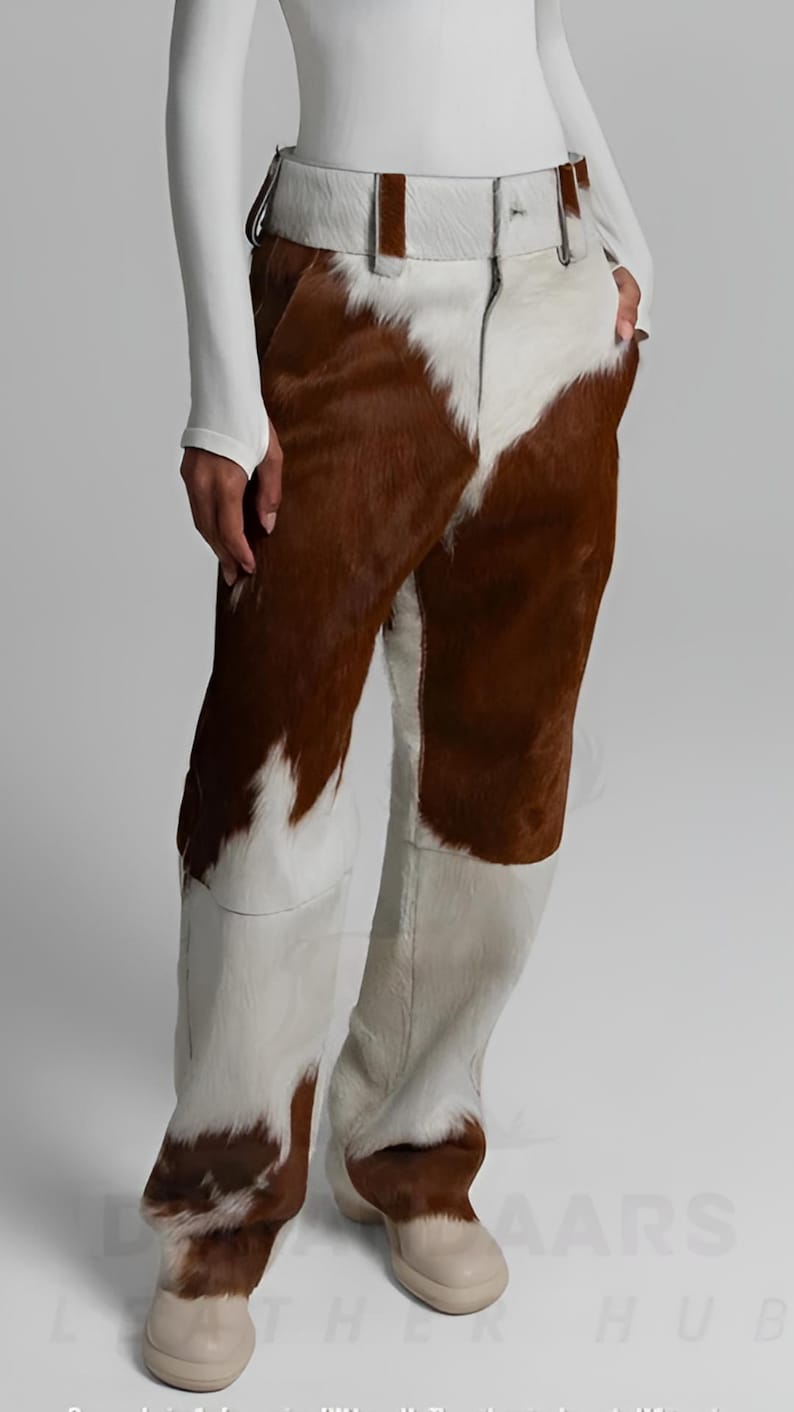 May include: Cowhide trousers in brown and white, featuring a distinctive pattern. The trousers have a matching belt and are made from a soft, textured material. Beige shoes complete the look.