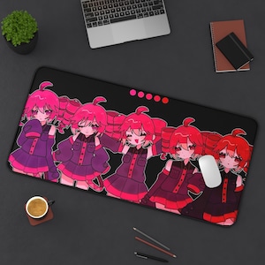 May include: Black rectangular desk mat featuring a repeating anime-style illustration of a girl with pink hair and a purple and pink outfit. A white mouse is on the mat. The mat is on a black desk.