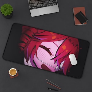 Könnte beinhalten: Schwarze rechteckige Schreibtischunterlage mit einer Nahaufnahme einer Anime-Illustration eines Charakters mit roten Haaren und Erröten. Eine weiße Computermaus befindet sich auf der rechten Seite der Matte. Ein Laptop, eine kleine Pflanze und Schreibwaren sind ebenfalls sichtbar.