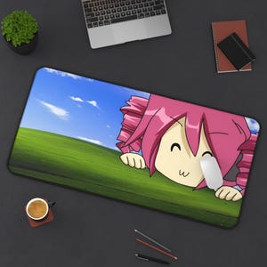 May include: A rectangular mousepad featuring a cartoon character with pink hair and a smiling face. The background depicts a green field under a blue sky with clouds. A white mouse rests on the pad.
