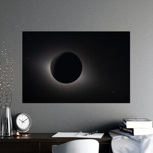 May include: A black and white print of a solar eclipse. The image shows the moon completely covering the sun, with a bright corona visible around the edges. The background is a dark, starry sky.