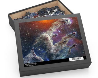 May include: A 16x20 inch, 500-piece jigsaw puzzle featuring a vibrant image of a nebula with orange, blue, and purple hues. The puzzle is in a black box with the puzzle image on the lid. The box is open, revealing some puzzle pieces.