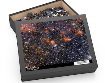 May include: A 16x20 inch puzzle box with a lid open, revealing puzzle pieces. The box features a vibrant image of a galaxy with stars and cosmic dust. The box reads "16x20 Puzzle 500 pcs Ages 9+".