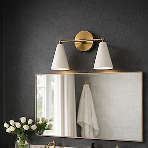 May include: A bathroom vanity featuring a rectangular mirror, two sinks, and brass taps. Above the mirror, a brass light fitting with two white cone shades. A vase of white tulips sits on the countertop.