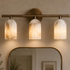 May include: A three-light wall fitting featuring a horizontal antique brass bar and a circular mounting plate. Three dome-shaped, vertically ribbed glass shades with a marbled white and tan finish hang downwards from the metal frame.