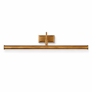 May include: A long, horizontal picture light fixture with a brushed brass finish. The design features a slender, cylindrical tube light attached to a rectangular wall-mounting plate by a single, central vertical arm with a curved neck.