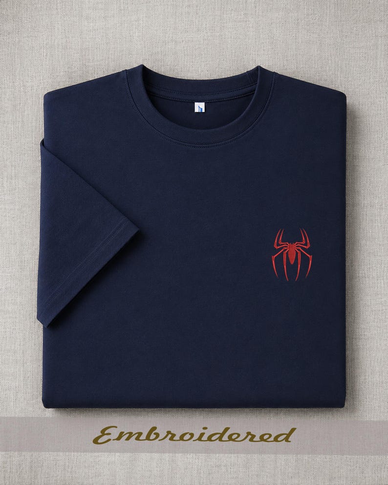 May include: Navy blue t-shirt with a red spider emblem embroidered on the chest. The shirt has short sleeves and a crew neck. The word "Embroidered" is printed in gold at the bottom of the image.