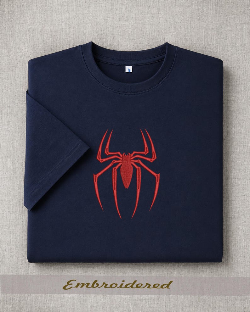 May include: Navy blue t-shirt with a red spider emblem embroidered on the front. The shirt has short sleeves and a crew neck. The word "Embroidered" is printed at the bottom of the image.