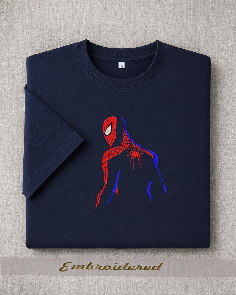 May include: Navy blue t-shirt featuring an embroidered Spider-Man design. The graphic depicts the superhero in red and blue, with the word "Embroidered" at the bottom. The shirt has a classic crew neck and short sleeves.