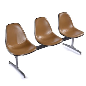 May include: A three-seat bench with brown seats and black trim. The seats are attached to a black metal bar and supported by silver-colored metal legs. The seats have a smooth, curved design.