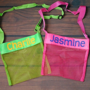 May include: Two mesh bags with adjustable straps. The green bag has the name "Charlie" embroidered on it in orange. The pink bag has the name "Jasmine" embroidered on it in blue.
