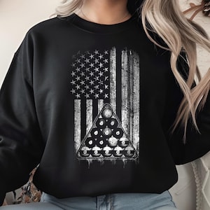 May include: Black sweatshirt featuring a distressed American flag design with a triangle of billiard balls. The graphic is in shades of white and gray, creating a vintage look. The sweatshirt is a casual, comfortable garment.