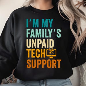 May include: Black sweatshirt with the text "I'M MY FAMILY'S UNPAID TECH SUPPORT" in teal, beige, orange, and white. The design includes a computer monitor icon with a wrench and screwdriver. A humorous gift for tech-savvy individuals.