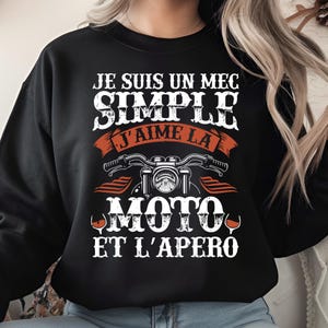 May include: Black sweatshirt with white text that reads "JE SUIS UN MEC SIMPLE J'AIME LA MOTO ET L'APERO" with a motorcycle graphic and wine glasses. The design is in a vintage style.