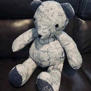 May include: A handmade teddy bear with a map-themed fabric design. The bear features a white background with a blue nautical map print, including ships and compasses. The ears and the soles of the feet are a solid blue. The text "CAMP SMITH" is printed on the foot.