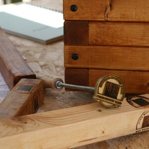 May include: A selection of wooden woodworking tools and a partially assembled wooden box are shown. The tools include a branding iron and wooden blocks, with the text "MADE IN BRAZIL" visible. The box is made from stained wood.