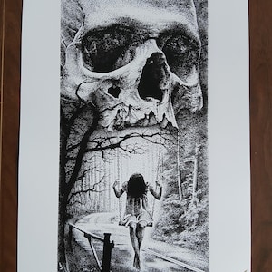 May include: Black and white art print featuring a large skull above a girl on a swing set. The girl is swinging on a swing set on a road that leads into a forest. The art is detailed with a stippling technique.