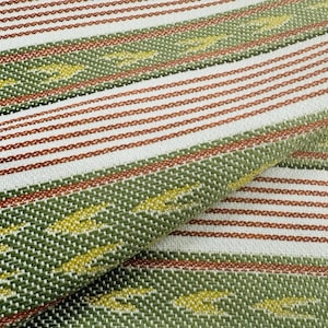 May include: Close-up of a woven fabric with a repeating pattern of stripes and geometric shapes. The fabric features alternating stripes of white, olive green, and rust-coloured threads. Yellow accents are woven into the green stripes.