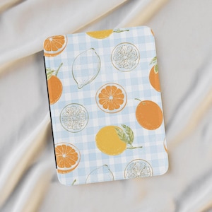 May include: A rectangular notebook with a light blue and white checkered pattern. The notebook is decorated with illustrations of oranges, lemons, and citrus slices. The illustrations are in orange, yellow, and green.