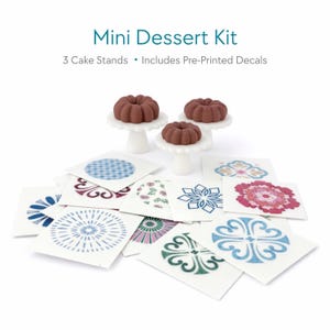 May include: A mini dessert kit with three small chocolate cakes on white cake stands, and pre-printed decorative decals. The decals feature various geometric and floral patterns in shades of blue, pink, and green. The text "Mini Dessert Kit" is at the top.