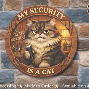 May include: Round wooden sign featuring a grumpy cat holding a flashlight. The sign reads "MY SECURITY IS A CAT" and "NO TREATS, NO ENTRY." The cat is brown and white with an angry expression. A lamp and a plant are visible.