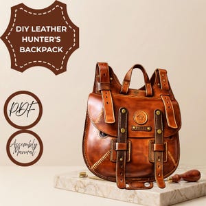 Pode incluir: Uma mochila de couro castanho com duas alças verticais com fivelas cor de latão, uma alça superior e um emblema circular. O texto DIY LEATHER HUNTER'S BACKPACK, PDF e Assembly Manual é visível juntamente com uma ferramenta de couro.