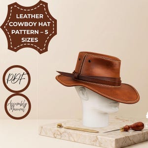 May include: A brown leather cowboy hat with visible stitching and a dark brown hatband, displayed on a white mannequin head. Text on the image reads: LEATHER COWBOY HAT PATTERN – 5 SIZES, PDF, and Assembly Manual. A metal tool and awl are present.