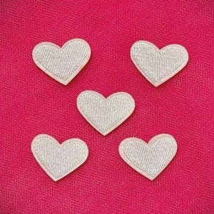 May include: Five white heart-shaped patches with a textured design are arranged on a vibrant pink fabric background. The hearts have a white border and are evenly spaced, creating a visually appealing pattern.