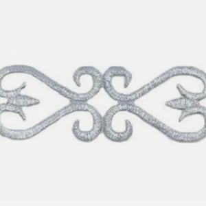 May include: A silver embroidered decorative applique with a symmetrical design. The applique features a repeating pattern of curved lines, swirls, and pointed leaf-like shapes. The design is centered on a white background.