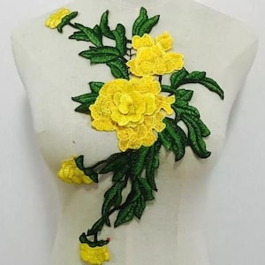 May include: Embroidered floral applique featuring vibrant yellow flowers and green leaves. The design showcases detailed stitching, creating a textured and dimensional effect. This decorative patch is suitable for embellishing clothing or accessories.