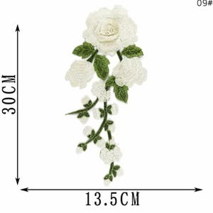 May include: White floral embroidered applique, approximately 11.8 inches long and 5.3 inches wide. Features a large rose and cascading smaller flowers with green leaves. Ideal for embellishing clothing or crafts.
