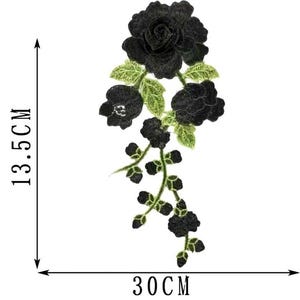 May include: Black floral embroidered applique, measuring 13.5 cm high and 30 cm wide. The design features a large rose, smaller buds, and green leaves. This decorative patch is suitable for clothing and craft projects.