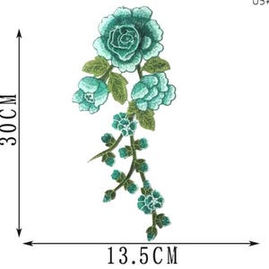 May include: Embroidered floral applique in shades of teal and green. The design features a large rose and several smaller blooms with leaves. The applique measures 11.8 inches in height and 5.3 inches in width.