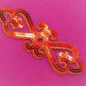 Puede incluir: Aplicación ornamental de lentejuelas en tonos rojos, naranjas y dorados, con un diseño en espiral en forma de corazón. La aplicación está delineada en dorado y tiene una apariencia texturizada, adecuada para adornar ropa o manualidades.