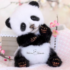 May include: A plush panda bear with black and white fur, black paws, and a friendly expression. The panda is holding its paws up and has the text "With love Lasienka" on its belly. Pink flowers are in the background.
