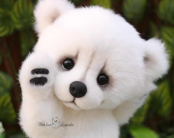 May include: A white teddy bear with black eyes, nose, and paw pads. The bear is raising its paw. The background features blurred green leaves. The text "With love Latenka" is visible at the bottom of the image.