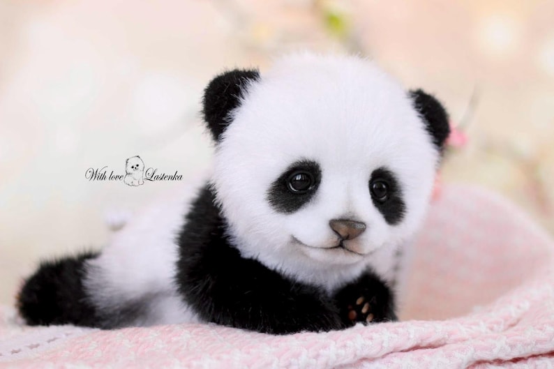 May include: A plush panda bear with black and white fur, lying on a pink blanket. The panda has black eyes and ears, and a small, smiling mouth. The image includes the text "With love Lostenka".