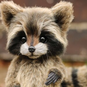 K&ouml;nnte beinhalten: Ein handgefertigtes Pl&uuml;sch-Waschb&auml;r mit detailliertem, realistischem Design. Der Waschb&auml;r hat ein braunes und graues Fell, schwarze Markierungen um die Augen und eine schwarze Nase. Das Pl&uuml;schtier hat einen freundlichen Ausdruck und ist ein Sammlerst&uuml;ck.