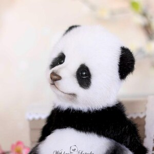 May include: A plush panda bear with a black and white color scheme. The panda has black fur on its legs, back, and ears, with white fur on its face and belly. The panda's eyes are black, and it has a brown nose. The panda is sitting.