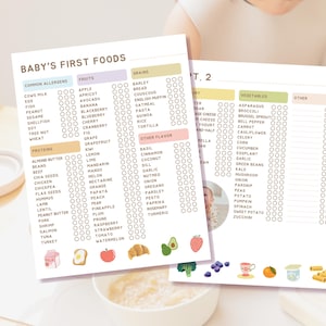 May include: Two checklists titled "Baby's First Foods" with sections for common allergens, fruits, grains, proteins, vegetables, and other flavors. The lists include illustrations of food items like an apple, avocado, and broccoli. The checklists are held by a person.