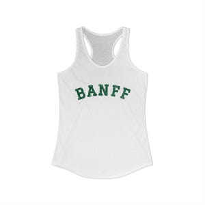 May include: White racerback tank top with the word "BANFF" printed in distressed green lettering across the chest. The tank top has a scoop neck and a racerback design. The garment is made of a soft, lightweight material.