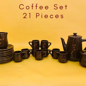 Puede incluir: Un juego de café de 21 piezas en cerámica marrón oscuro. El juego incluye una cafetera, una jarra de crema, un azucarero, tazas y platillos. Las piezas tienen un diseño sencillo con un patrón de granos de café.