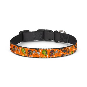 May include: Orange dog collar with a black buckle and a silver metal loop. The collar features a repeating pattern of racing helmets, checkered flags, and stars. The collar is approximately 1 inch wide.