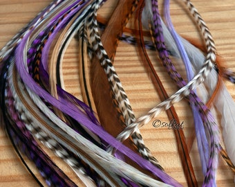 May include: A collection of colorful feather hair extensions in shades of purple, brown, white, and black. The feathers are long and flowing, and they are perfect for adding a touch of bohemian style to any hairstyle.