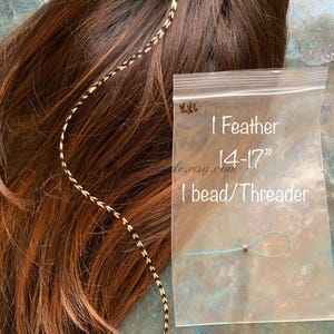 1 XXL hair feather shown against brown hair with 1 silicone bead and floss threader in a clear polybag