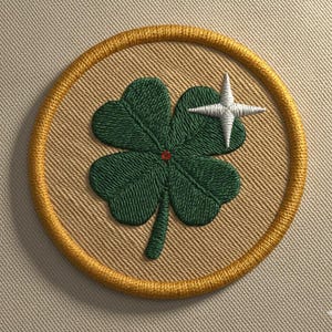 Puede incluir: Parche bordado con un trébol verde de cuatro hojas y una estrella blanca sobre un fondo beige, rodeado por un borde dorado. El parche redondo tiene un aspecto texturizado. El trébol tiene un pequeño centro rojo.
