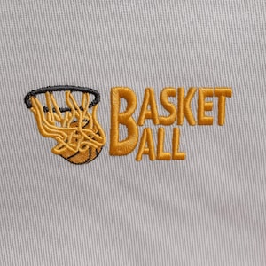 May include: Embroidered patch with a basketball net and ball, and the word "BASKETBALL" in gold thread. The design is on a light grey fabric, showcasing a sports theme.