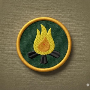 May include: Circular embroidered patch with a campfire design. The patch has a green background, a yellow and orange flame, black logs, and a gold border. It's likely designed to be sewn onto clothing or bags.