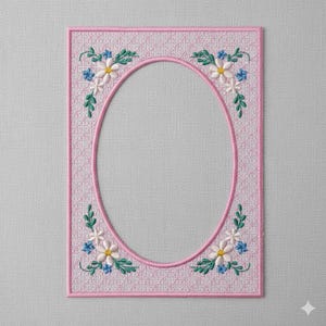 May include: A pink embroidered picture frame with an oval opening. The frame is decorated with embroidered white and yellow flowers, blue accents, and green leaves. The frame has a textured background.